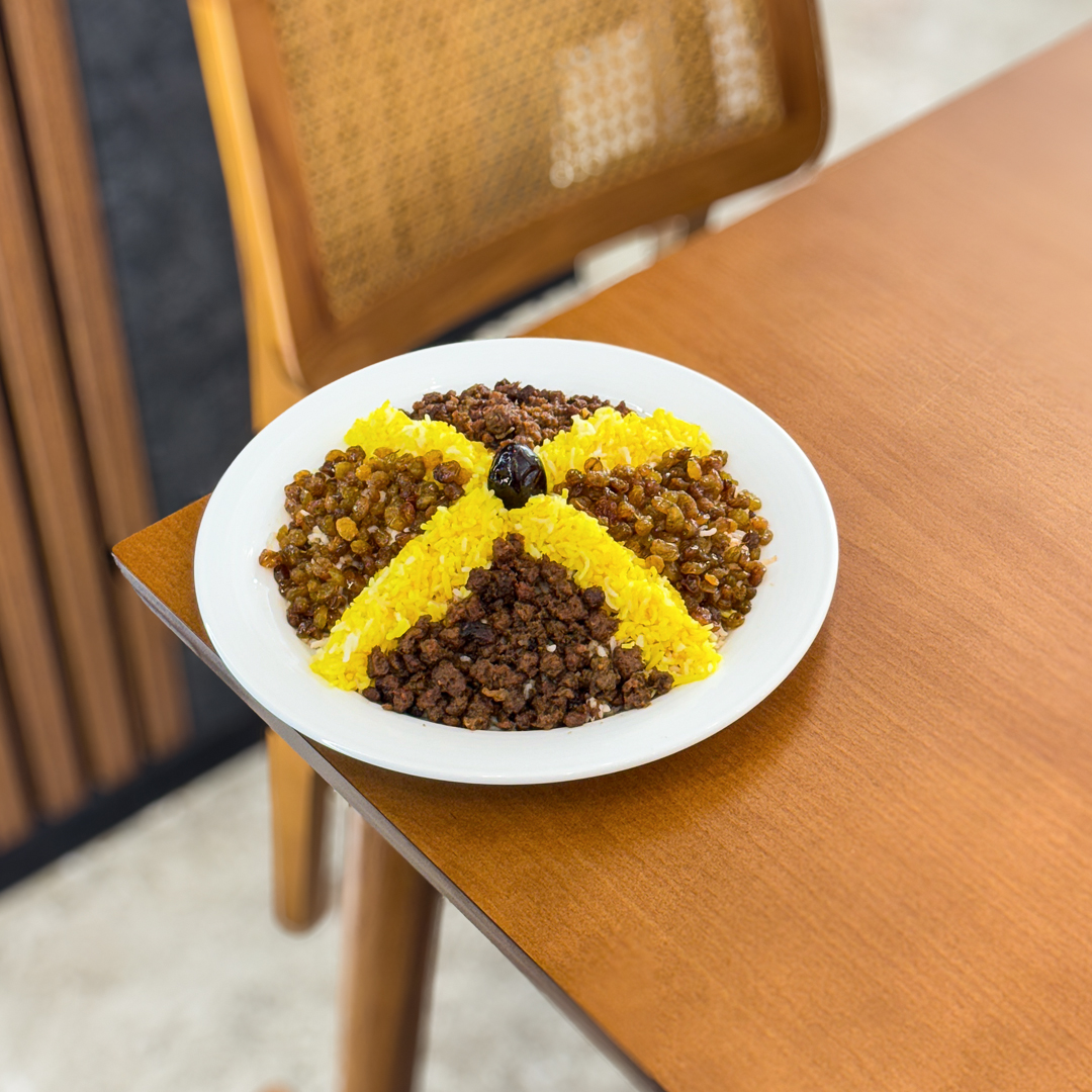 An Indian woman wearing a traditional sari wrap is using a taper to light a whole wall filled with hundreds of little oil lamps. They are illuminated and casting a bright glow over the scene; each lamp is set in its own little box within the wooden wall structure, tied with supporting pieces of bamboo. There are bunches of tiny bananas also tied to the top of the wall case.