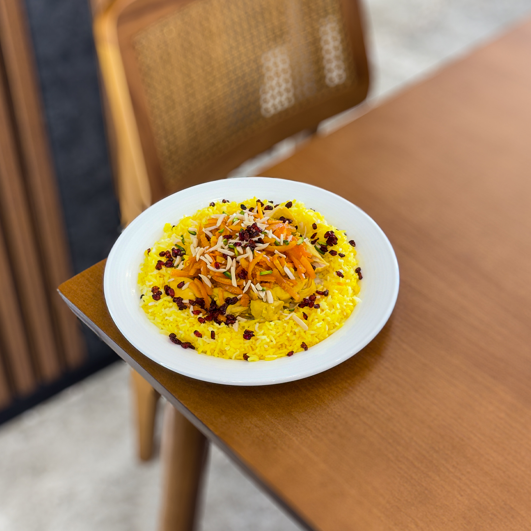The flat facade on a white adobe building is punctuated by three doors — blue, yellow and red — and two windows with yellow panes. The sky behind the building is blue and cloudy.